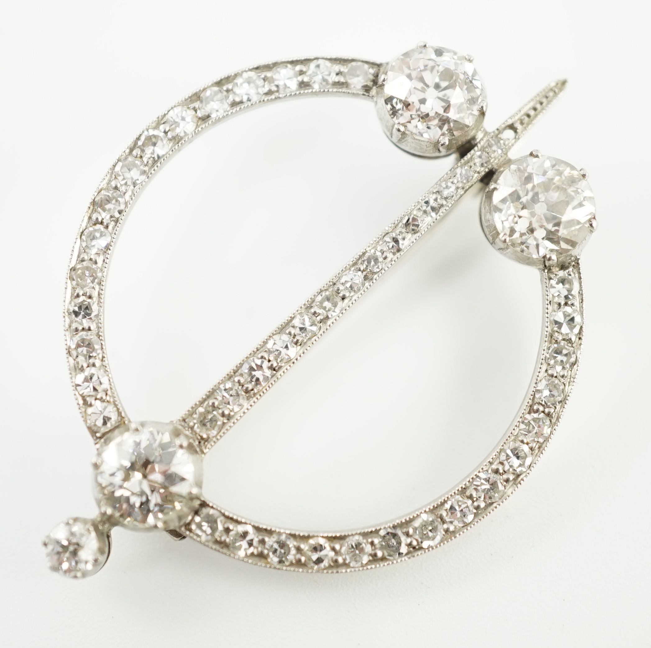 A 1920's platinum or white gold, diamond cluster set openwork 'dagger and circle' brooch